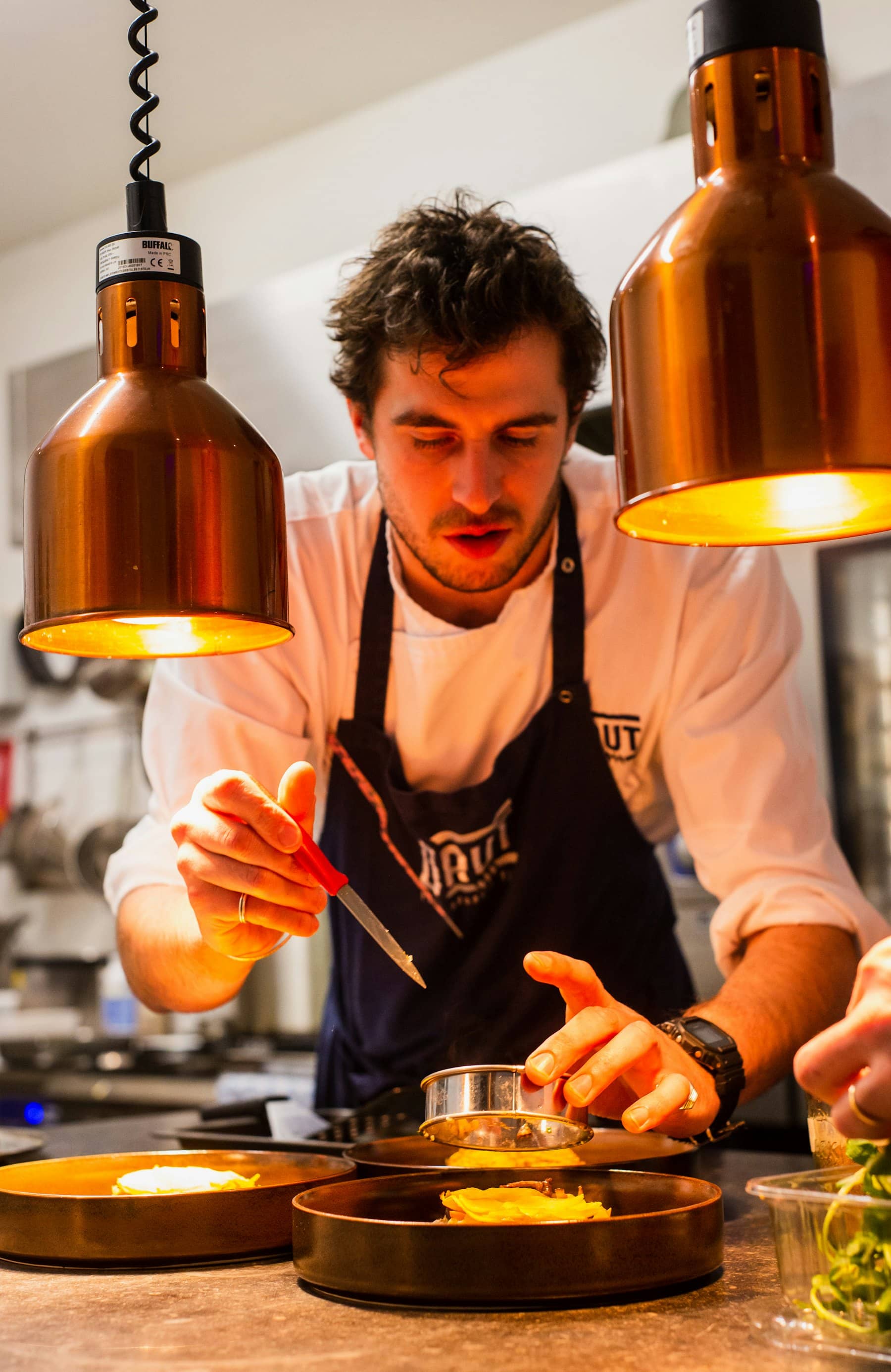 A chef plating under the heat lamps at the pass